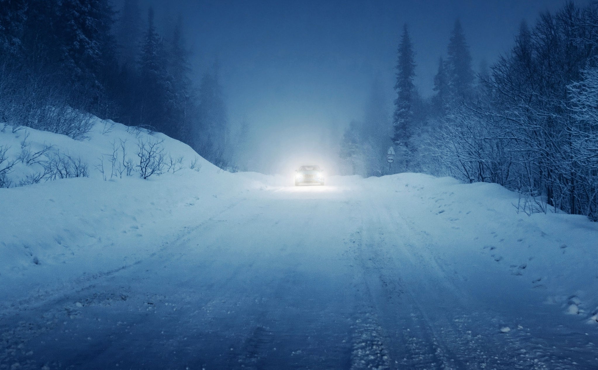 lights of car and winter road in forest